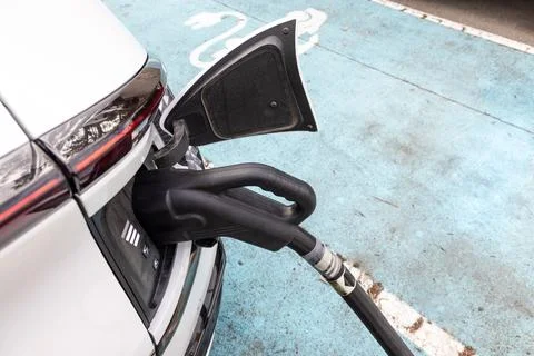 Closeup of EV car plugged in with fast charger at charging station. Stock Photos