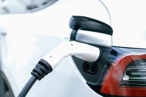 Closeup EV charger plug handle attached to electric vehicle port. Synchronos Stock Photos