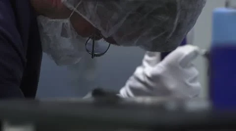 Closeup of Face and Hands with Out-of-Focus Foreground in Cleanroom Stock Footage 10895367