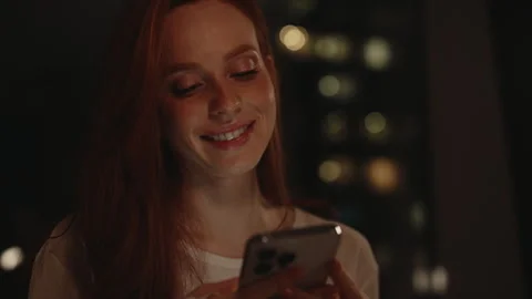Closeup face of charming red-haired woman browsing smartphone sitting by window Stock Footage 304874414