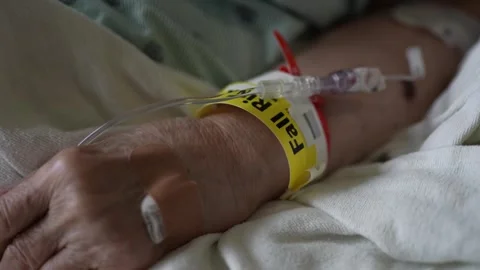 Closeup of Fall Risk wristband on elderly womans hand while lying in hospital 스톡 동영상 285148981