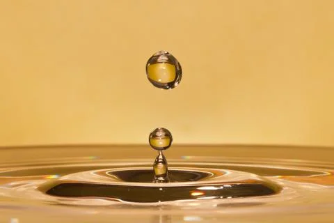Closeup of falling water-drop in a yellow liquid Stock Photos