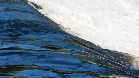 Closeup of fast flowing clear water in river, flowing over a dam Видео 112766902