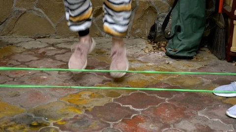 Closeup of feet jumping over elastic band in the back yard. active games Видео 127777424