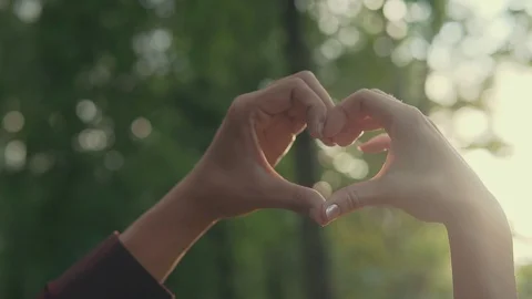 Closeup of female and male hands showing heart shape at sunset. Love Stock Footage