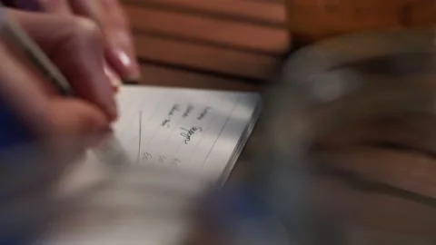 Closeup of a female hand making notes in a notebook. calculations on paper Stock Footage 141413242