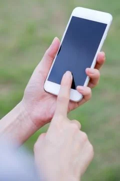 Closeup of female hand using a mobile phone on farm background Foto stock