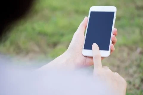 Closeup of female hand using a mobile phone on farm background Stock Photos