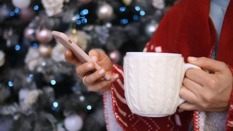 Closeup Of Female Hands With Cup Using Phone In Cozy Xmas Home Atmosphere Stock Footage 98330124