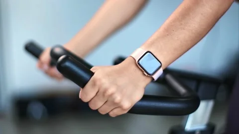 Closeup female hands holding by handle of exercise bike during cycling. 4k Stockbeeldmateriaal 135440887