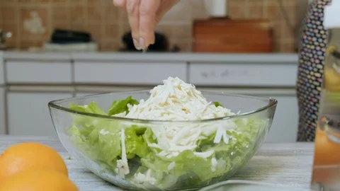 Closeup of female hands putting salt into a plate of vegetable salad on the t Stock Footage 121660341