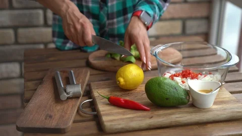 Closeup of female hands squeezing half a lemon to avocado for guacamole at table Vídeos de archivo 91755019