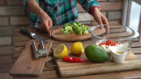 Closeup of female hands squeezing half a lemon to avocado for guacamole at table Stock Footage 91755138