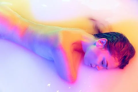 Closeup female hips, bottocks in the milk bath with soft pink neon glow. Beauty Stock Photos