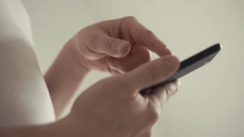 Closeup female relaxes in home using smartphone scrolling on text message or Video stock 336249723