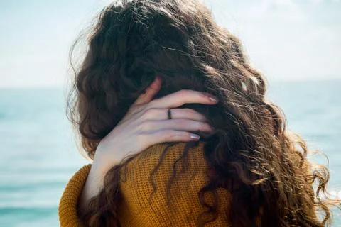 Closeup of female sitting on a beach and touching her shoulder with her hand Stock Photos