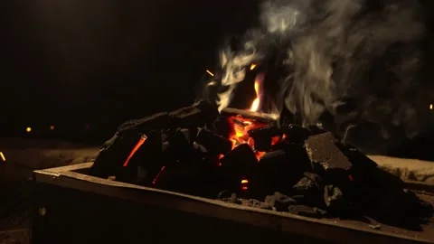 Closeup of fire coming out of burning coals over a chinese grill box at night in Stock Footage 199592297