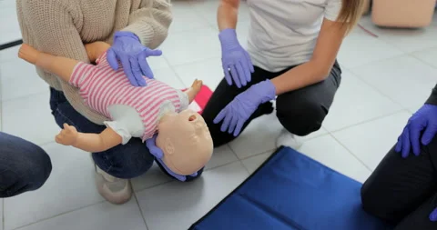 Closeup of first aid instructor using infant dummy demonstrating how to rescue a Stock Footage 163977326