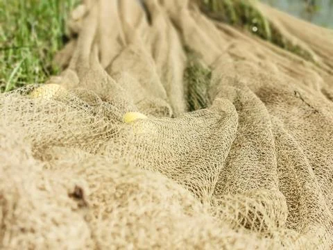 Closeup of a fish net kept on the side of a pond Stock Photos