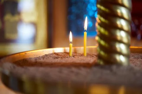 Closeup of flame of a single burning red candle light in a dark chirch mourning Stock Photos
