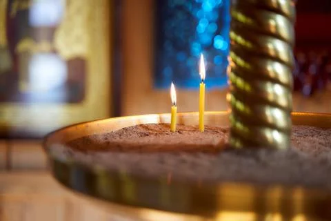 Closeup of flame of a single burning red candle light in a dark chirch mourning Stock Photos