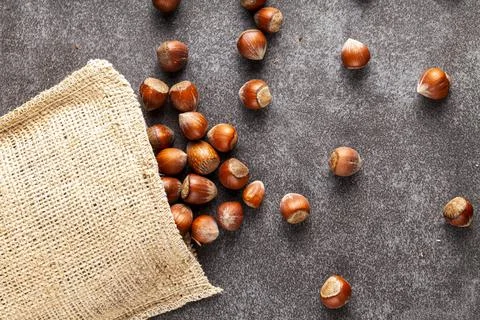 Closeup flat lay image of hazelnuts in shells scattered from a vintage burlap Stock Photos