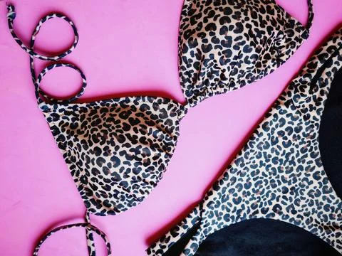 Closeup of a flat lay with a leopard bikini on pink background Stock Photos
