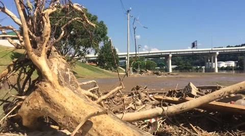 Closeup of Flood Debris in Foreground of Bridge and Traffic Stock Footage 64936907