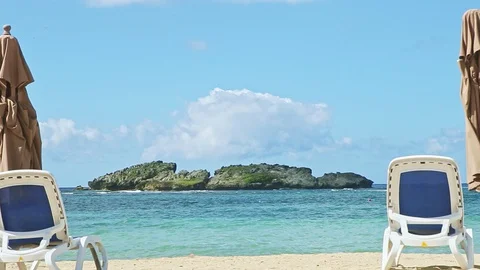 Closeup fluffy clouds fly above ocean and sand with beach chairs and closed Video stock 128395430