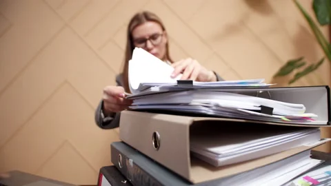 Closeup of folders with working office documents, against background of woman Stock Footage 183404198