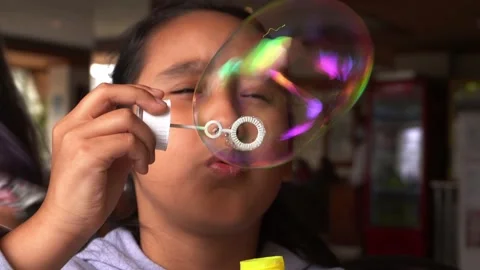 Closeup following a big rainbow colored soap and water bubble made by a little 库存影片 167293187