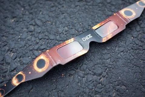 Closeup footage of a solar eclipse glasses with protection on black asphalt Fotos de archivo