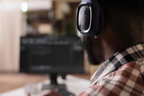 Closeup on freelance coder with wireless headphones listening to music while Stock Photos