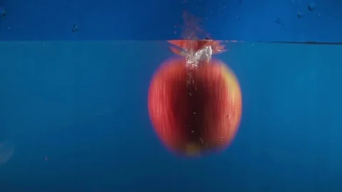 Closeup of fresh red apple falling into water on the blue backgrond slow motion Stock Footage 75787902