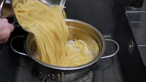Closeup of freshly boiled spaghetti being drained off in the strainer Видео 262561300