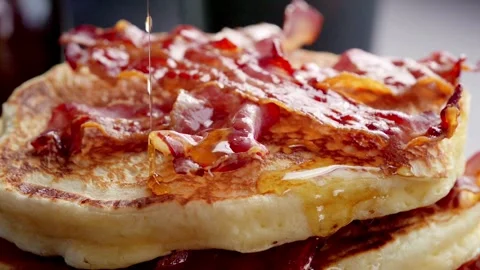 Closeup of fried bacon on a stack of delicious pancakes. Video stock 336589113