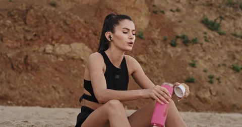 Closeup in front of the camera thirsty lady drinking water from a sport pink Video stock 115330160