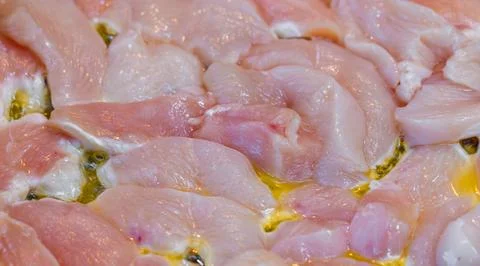 Closeup full-frame background of raw chicken breast meat just starting to roast Stock Photos