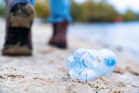 Closeup garbage plastic bottle thrown by female on city beach. Trash on natur 스톡 사진