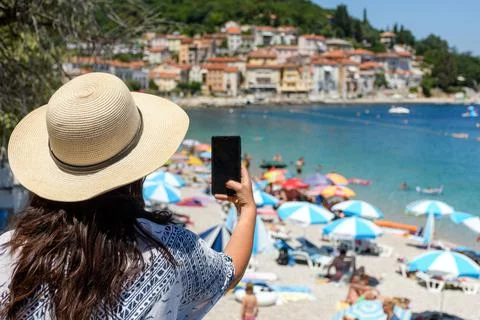 Closeup of a girl taking photos of the crowded beach in Moscenicka Draga in Croa Stock Photos
