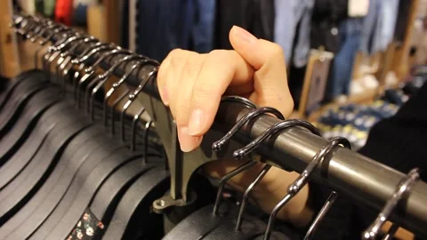 Closeup girld hand lays at a rack with hangers Stock Footage 123722056