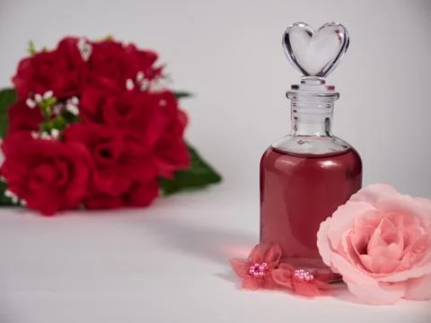 Closeup of a glass bottle of perfume with artificial pink roses on the whit.. 스톡 사진