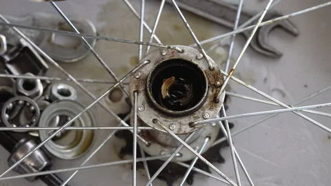 Closeup of a gloved hand cleans the rear hub of a bicycle wheel. Wash bike parts Stock Footage 115507652