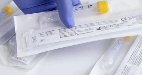 Closeup of Gloved Hand Picking Up and Checking COVID Swab Kit Stock Footage 129415685