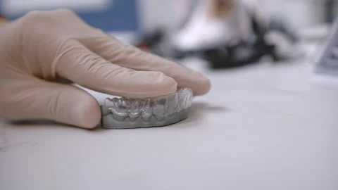 Closeup of gloved hand puts dental aligner on impression mold Stock Footage 306765279