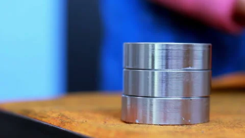 Closeup gloved hand stacking machined steel rings. Metal bearing parts workshop. Stock Footage 345678252