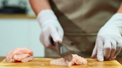 Closeup of gloved hands mincing raw chicken on wooden board, showcasing foo.. Stock Footage 312979538