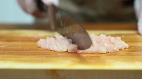 Closeup of gloved hands mincing raw chicken on wooden board, showcasing foo.. Video stock 312979545