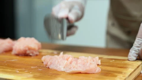 Closeup of gloved hands mincing raw chicken on wooden board, showcasing foo.. Stock Footage 312979697