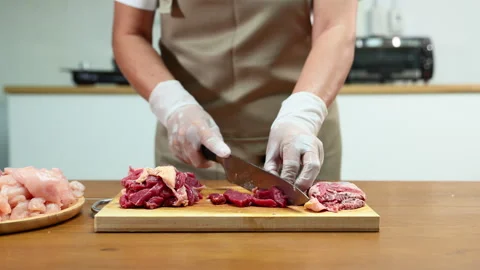 Closeup of gloved hands slicing raw beef steak on a wooden board. Ideal for.. Stock Footage 312980384